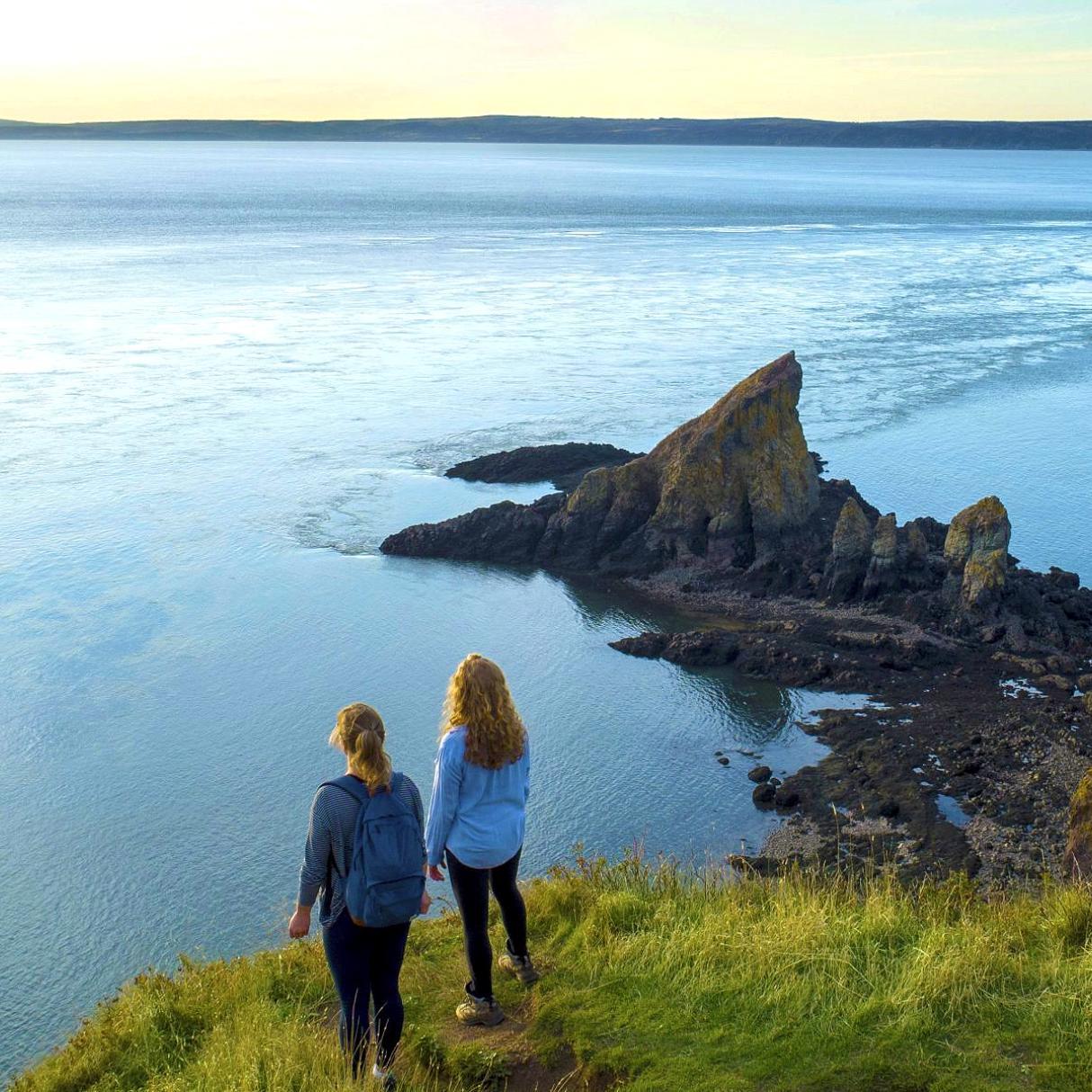 2 people look out over a coastal cliff