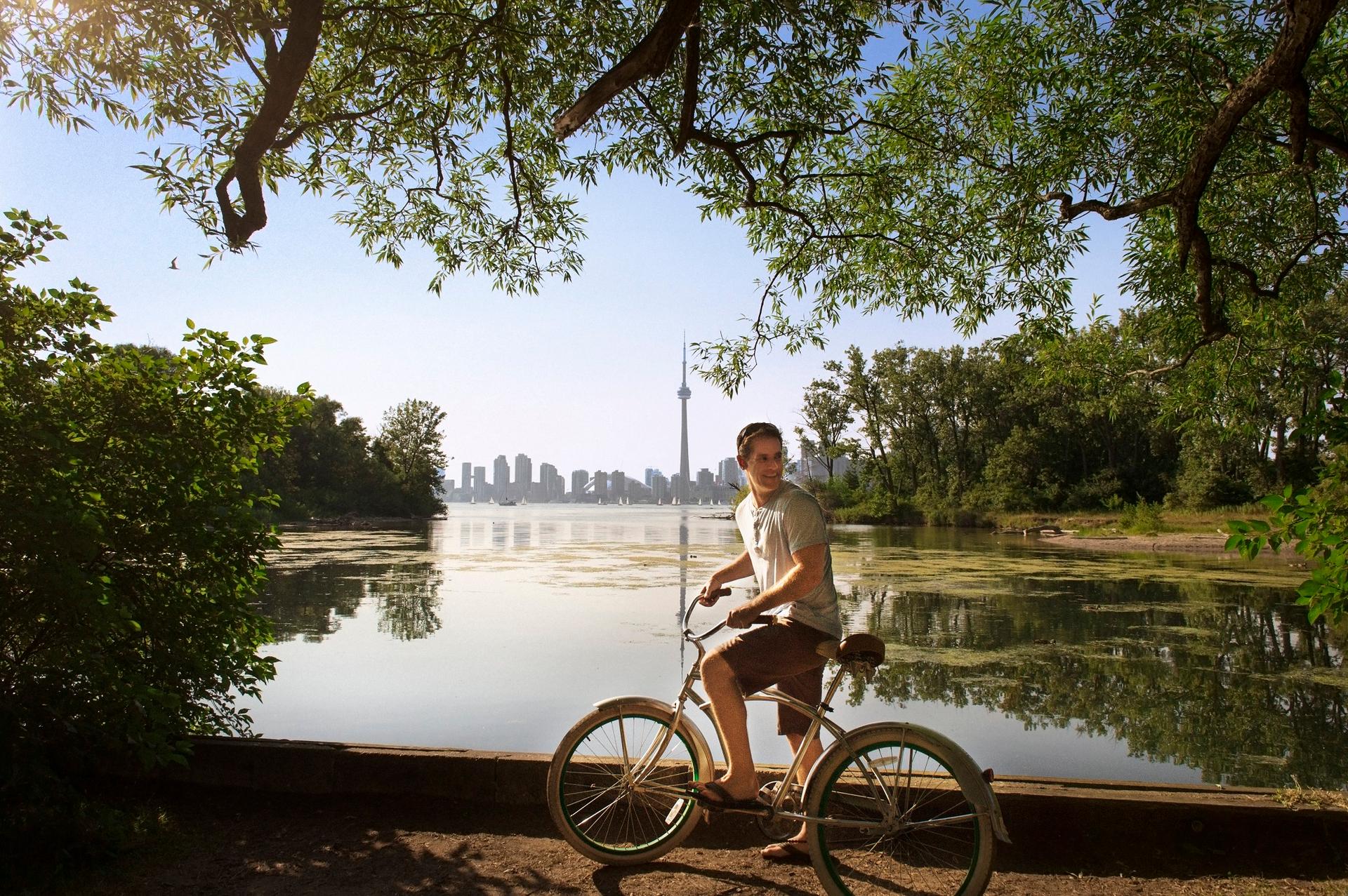 A cyclist rides on a bike path in view of the CN Tower in Toronto